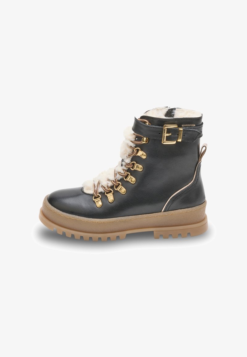 Botín negro de cuero con forro de piel sintética, herrajes en tono dorado y suela de goma marrón. Presenta un cierre de cordones en la parte delantera y un detalle de hebilla en el lateral.