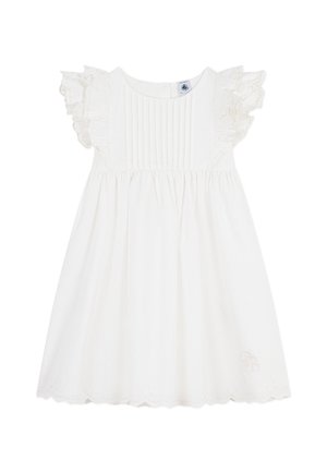 Valkoinen puuvillamekko, jossa on lyhyet röyhelöhihat, laskostettu yläosa, laskeutuva helma ja aaltoileva helmareuna. Mekossa on hienovaraisia kirjailtavia yksityiskohtia.