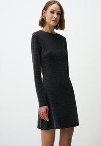 Abito lungo nero a maniche lunghe dal design aderente, con una leggera texture lucida, scollatura a girocollo e orlo svasato.