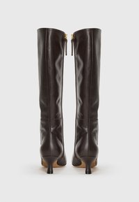 Stivali alti in pelle marrone con un design aderente, dotati di un tacco basso e doppie cerniere sul retro per una facile indossabilità.
