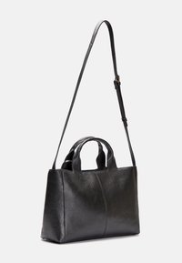 Černá texturovaná kožená kabelka s krátkými uchy a dlouhým nastavitelným ramenním popruhem na jednoduchém bílém pozadí.