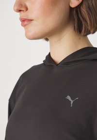 Felpa con cappuccio nera, realizzata in tessuto morbido, con un piccolo logo riflettente Puma sul lato sinistro del petto.