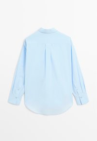 Camicia da uomo a maniche lunghe di colore azzurro con colletto classico e polsini con bottoni, vista da dietro su uno sfondo bianco.