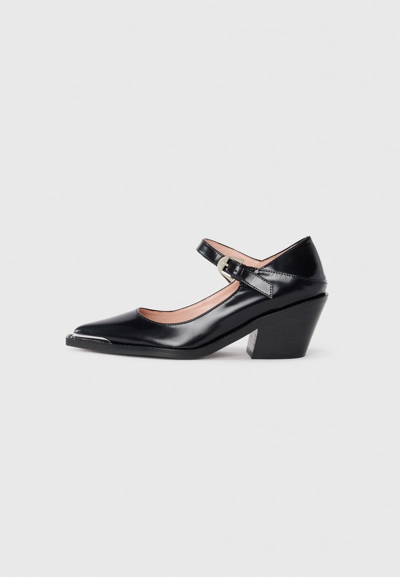 Black patent leather Mary Jane heels with a pointed toe, ankle strap, and block heel. Features a shiny silver toe cap detail.