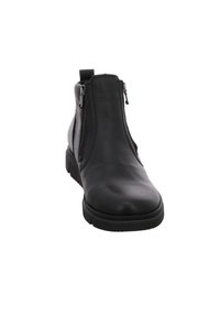 Schwarze Knöchelstiefel mit einer glatten Leder-Oberfläche, ausgestattet mit zwei seitlichen Reißverschlüssen, einer runden Zehenpartie und einer strukturierten Gummisohle für besseren Halt.