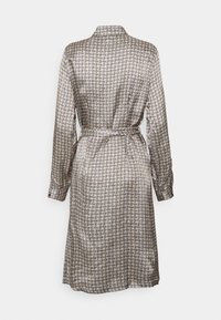 Long-sleeve, patterned dress in beige with dark text. Features a collared neckline, a belted waist, and a straight cut, with a mid-length hem.