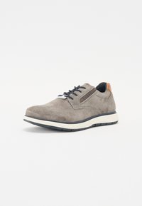 Grå semsket sneakers med perforert tekstur, marineblå snøringer og en brun lærdetalj på hælen. Hvit mellomsåle og slitesterk yttersåle.