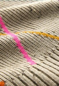Kootud tekstiil, millel on beež alus, tekstuursete soontega, mida kaunistavad elavad roosa ja oranži diagonaalis olevad jooned.