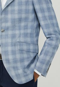 Jasnoniebieski marynarka w kratę wykonana z teksturowanej tkaniny, z klapami w kształcie litery notched, dwoma guzikami i jedną kieszenią po lewej stronie.
