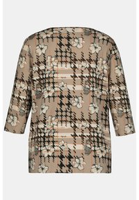 Mönstrad topp med blommönster på en beige bakgrund, med svarta och orange accenter, trekvartsärmar och en lös passform.