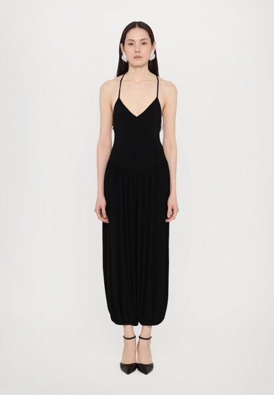 Combinaison noire sans manches avec un décolleté en V profond, design à jambes larges plissées et ourlet effilé à la cheville, fabriquée en tissu doux.