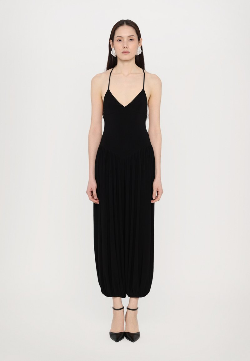 Schwarzer ärmelloser Jumpsuit mit tiefem V-Ausschnitt, plissierter, weit geschnittener Beinform und knöchellangem, schmal zulaufendem Saum, aus weichem Stoff gefertigt.