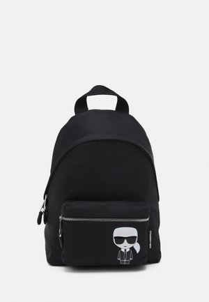 Černý batoh s přední kapsou na zip, na které je kreslená postavička s slunečními brýlemi a oblekem, s copem.