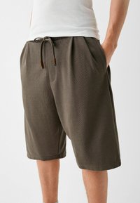 Šedé bavlněné šortky s elastickým pasem, nastavitelnou šňůrkou, bočními kapsami a texturovaným materiálem.