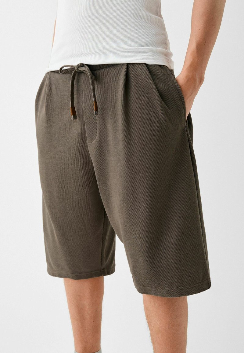 Šedé bavlněné šortky s elastickým pasem, nastavitelnou šňůrkou, bočními kapsami a texturovaným materiálem.