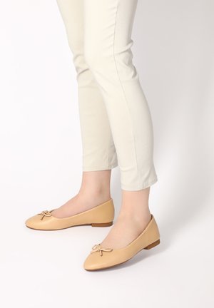 Beige kožené baleríny s kulatou špičkou a malou mašličkou. Nízký hnědý gumový klínek; hladká textura a minimalistický design.