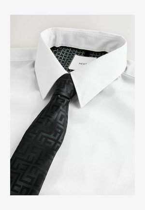 Witte dress shirt met een gestructureerde kraag, gecombineerd met een zwarte stropdas met een geometrisch patroon. De binnenkant van de kraag toont een hexagonaal ontwerp.