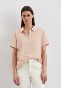 Lichtroze polo shirt met een kraag, korte mouwen en een knoopsluiting. Kenmerkt zich door een subtiel logo op de borst en een zachte stofstructuur.