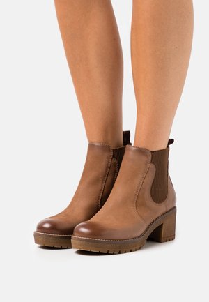Botas de tobillo de cuero marrón con paneles laterales elásticos, punta redonda y tacón de bloque de 4 cm. Acabado texturizado y suela de goma con detalles antideslizantes.