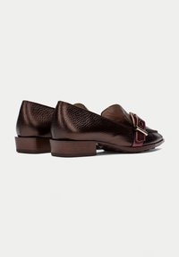 Ballerine in pelle marrone scuro con una finitura tessurizzata, dotate di un cinturino prominente con un particolare a fibbia e un tacco basso in legno impilato.