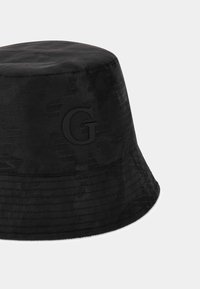 Czarna czapka typu bucket z teksturowanym wzorem krokodylej skóry, z matowym, wytłoczonym logo „G” z przodu oraz prostym, zaokrąglonym brzegiem.