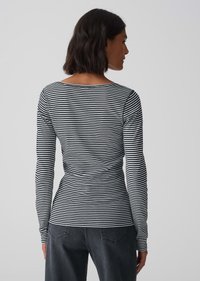 Langärmliges Oberteil mit schwarz-weißen Streifen, rundem Ausschnitt und figurbetontem Design. Das Material scheint dehnbar zu sein und reicht bis zu den Handgelenken.