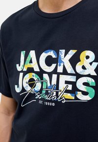 Navyblaue Baumwoll-T-Shirt mit auffälligem, mehrfarbigem Text "JACK & JONES Essentials" im Farbspritzdesign und geschwungenen Akzenten.