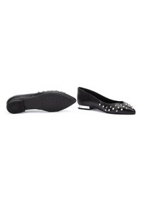 Zapatos planos negros con puntera puntiaguda, adornados con tachuelas plateadas, que cuentan con un pequeño tacón cuadrado y suelas de goma texturizada.