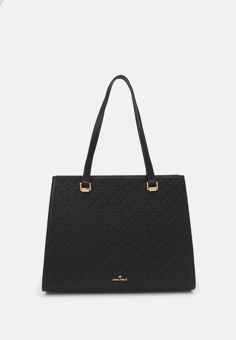 Sac à main rectangulaire noir avec motif géométrique en relief, logo de marque doré et doubles bretelles.