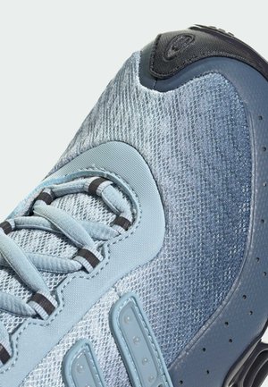 Gros plan d'une basket bleu clair avec un matériau en mesh texturé, un design à lacets, des accents noirs et des détails sur la semelle en caoutchouc.