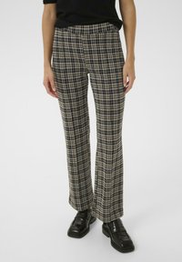 Svart, blå och beige rutiga utsvängda byxor med elastisk midja. Kombineras med svarta loafers för en komplett look.