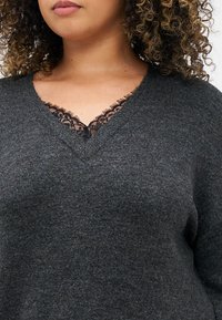 Dark gray knit sweater with a V-neckline featuring delicate black lace trim. Soft texture, relaxed fit, and minimal design details.