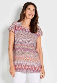 Kurzärmeliges, gemustertes Oberteil mit einem Wellendesign in Rosa, Lila und Weiß, runder Halsauschnitt und Knopfdetails auf der Vorderseite.