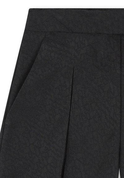 Pantalons noirs avec un motif texturé, devant plissé et une taille lisse, fabriqués en un tissu tissé doux.