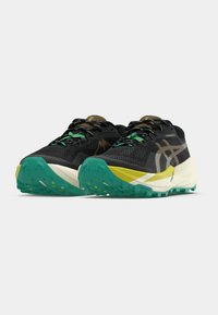 Chaussures de trail noires avec une tige texturée, des accents verts et jaunes, une semelle extérieure turquoise antidérapante et une semelle intermédiaire blanche légère.