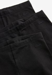 Melnas stiepjamās legingi ar elastīgu jostasvietu, ar smalku "Clarks" logotipu tumšā pavedienā, gluda tekstūra un vienkāršs dizains.