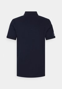 Marinblå pikétröja med platt krage, korta ärmar och en logodetalj på ärmen. Tillverkad av mjukt bomullsmaterial.