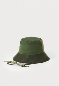 Groene bucket hat met een brede rand, gemaakt van een gestructureerde stof, met een twee-kleurig ontwerp en een versierde kinband met een strikdetail.