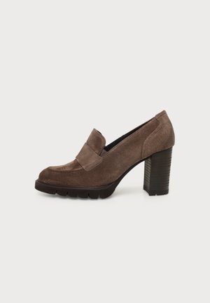 Brun ruskind loafer med høj hæl, kraftig hæl og tyk sål med slidbane, set fra siden mod en hvid baggrund.