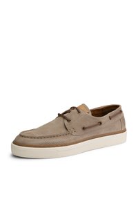 Zapatos de barco de ante beige con paneles laterales perforados, cordones marrones, cuello acolchado y suela de goma blanca. Detalles de costura a lo largo de los bordes.