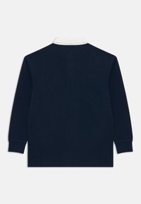 Polo de manga larga navy con cuello blanco. Presenta un color sólido, puños acanalados y un corte relajado. Textura de algodón suave.