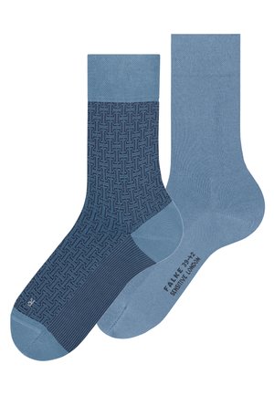 Par de calcetines azul marino, uno con patrón geométrico y el otro liso azul con texto negro en la suela, mostrados lado a lado.