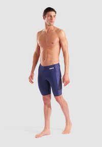 Herren-Badehose in Dunkelblau mit strukturiertem Seitenpanel; figurbetonter Schnitt und knielange Länge; der Stoff wirkt glatt und elastisch.