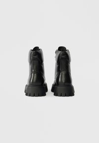 Μαύρες δερμάτινες μποτίνες με λείκτη υφή, στρογγυλή μύτη και χοντρή, ανθεκτική σόλα με βαθιές αυλακώσεις για καλύτερη πρόσφυση.