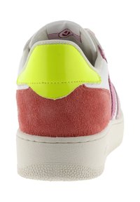 Baskets avec une tige en cuir blanc, un talon en daim rose et un accent en néon jaune brillant à l'arrière. Semelle en caoutchouc texturée.