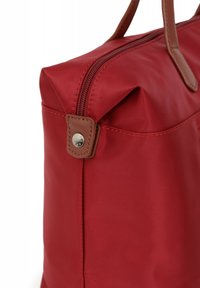 Borsa in nylon rosso con chiusura a zip, dettagli in pelle marrone e forma piatta. Presenta un bottone a pressione e una semplice cucitura lungo i bordi.