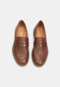 Mocasines de cuero marrón con textura trenzada, cinta ancha en el empeine, punta redondeada y costuras de suela en contraste.