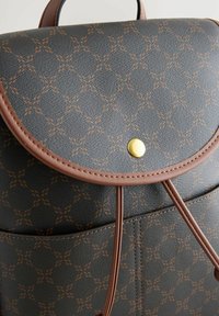 Sac à dos en cuir marron avec une surface texturée noire ornée d'un motif géométrique orange, rabat arrondi et fermeture à pression dorée.