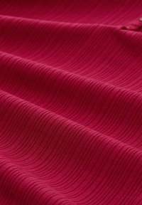 Textiles in tiefem Magenta mit subtilen Wellenmustern. Weiche, glatte Oberfläche mit einem leichten Glanz und gleichmäßigen, konsistenten Faltenlinien.