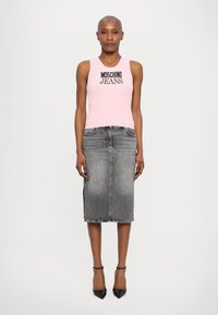 Top de alças rosa com nervuras e a marca "Moschino Jeans", combinado com uma saia de ganga cinza de comprimento médio e sapatos de salto pretos de bico.